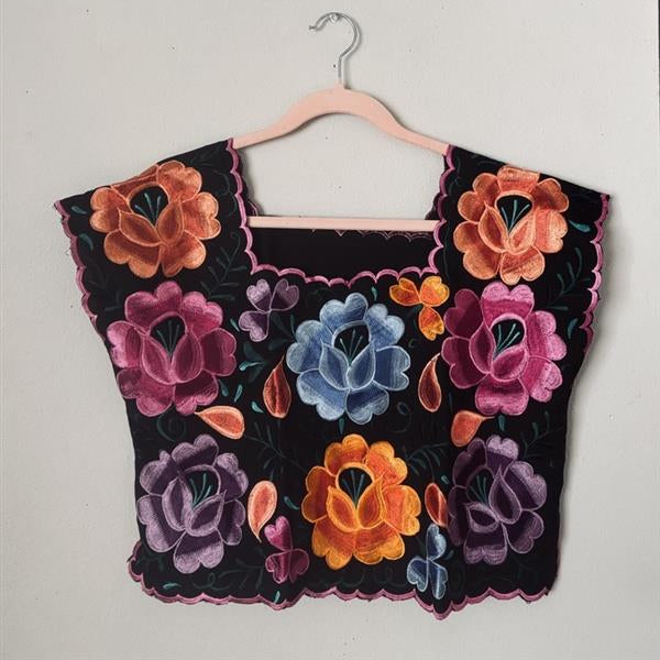 Mexican Black embroidered floral top on a hanger against a light gray background
